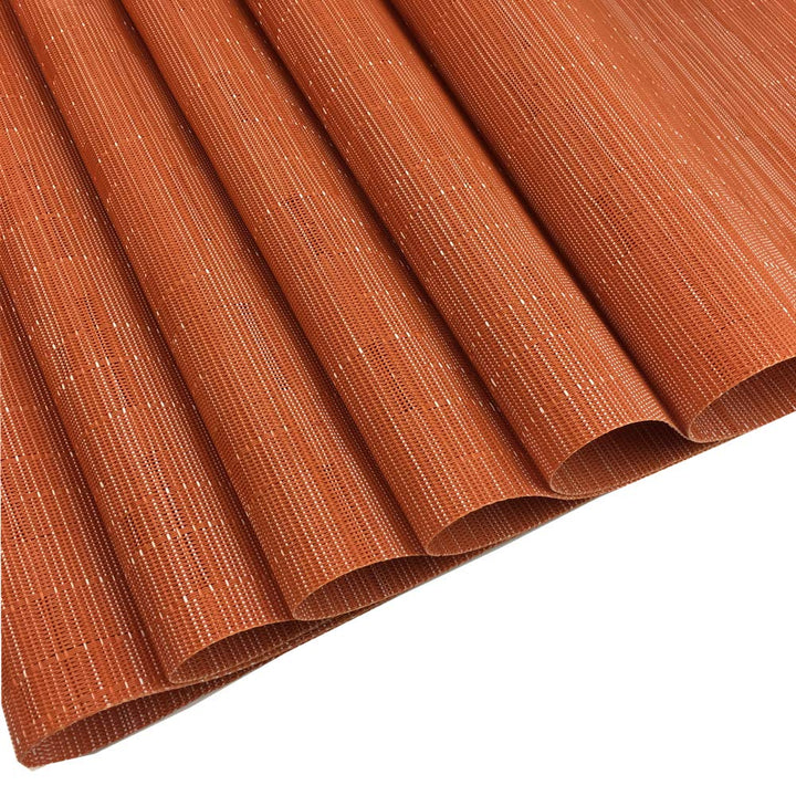 Sechs orange Platzsets ordentlich übereinander für die saisonale Tischdekoration