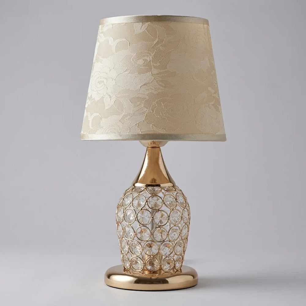 Nahaufnahme des Kristallfußes der Tischlampe mit goldenem Trommelschirm