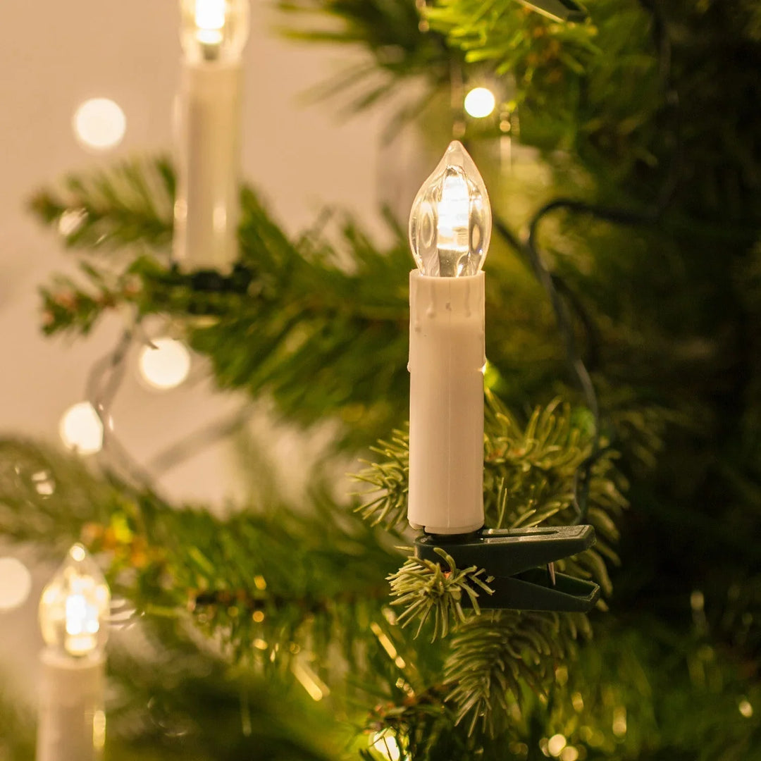 Detailansicht einer warmweißen LED-Clipkerze an einem Weihnachtsbaumzweig